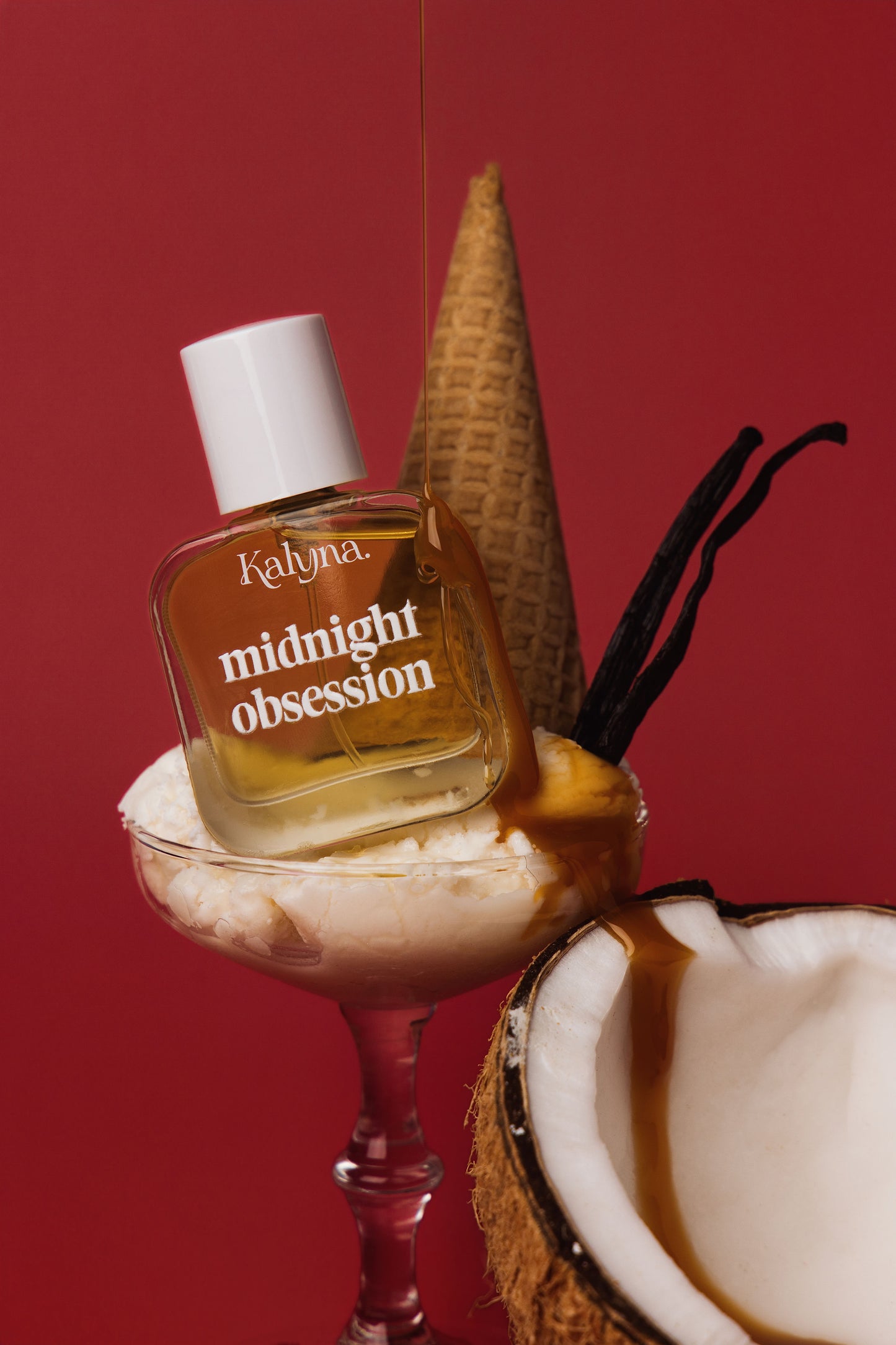 Kalyna midnight obsession perfume bottle with a coconut and vanilla bean on a red background