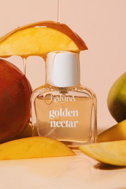 Perfume bottle labeled 'golden nectar' surrounded by mangoes on a beige background